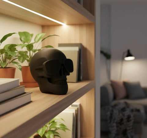 Altavoz Bluetooth Skull negro mate con gafas de sol en repisa de madera