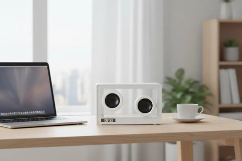 Altavoz Bluetooth transparente blanco sobre escritorio junto a un ordenador portátil