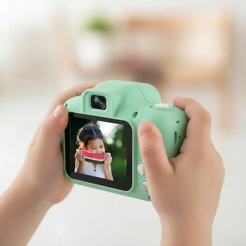 Cámara fotos HD para niños en verde menta con pantalla LCD mostrando foto de niña comiendo sandía