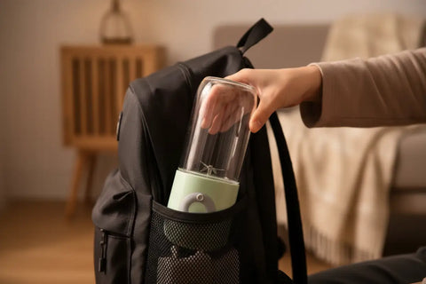 Persona sacando una batidora portátil verde de su bolso para usarla fuera de casa