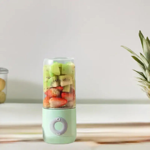 Licuadora eléctrica portátil verde llena de fruta para batidos, diseño funcional