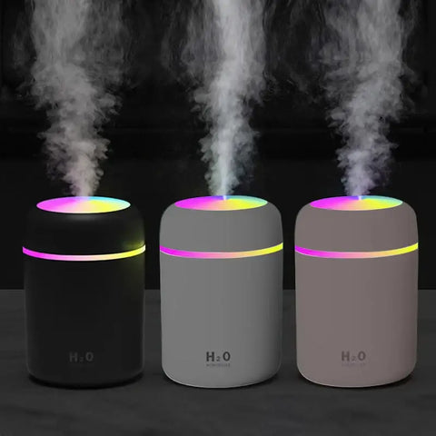 tres humidificadores que emiten vapor con bandas de luz de colores.