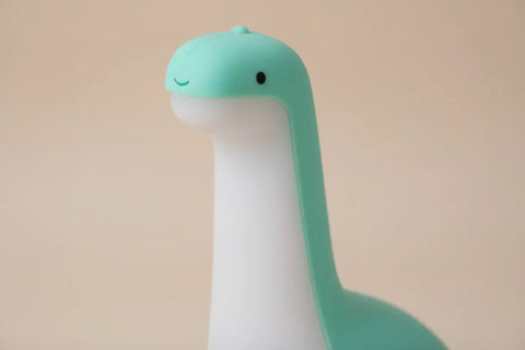 Luz nocturna dinosaurio de silicona teal y blanca con sonrisa suave