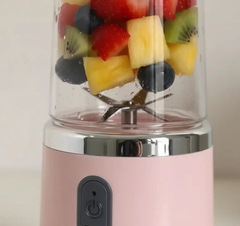 Primer plano de licuadora portátil con 6 cuchillas de acero inoxidable y frutas troceadas.